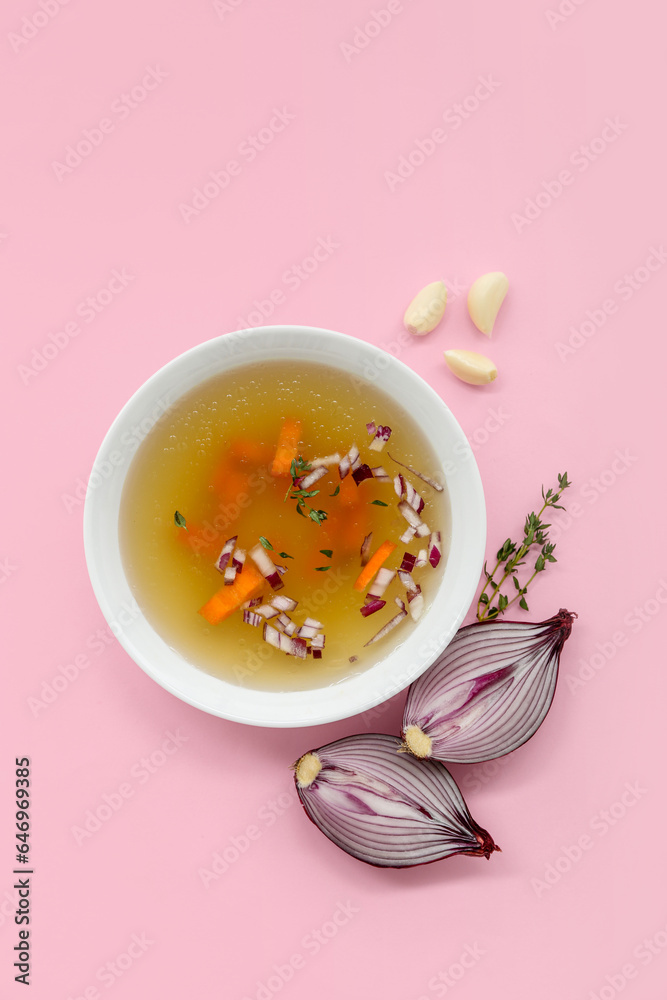 Bowl of tasty vegetable broth on pink background