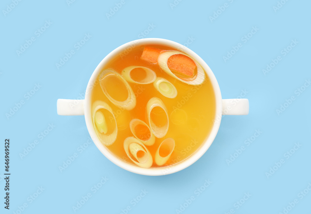 Pot of tasty vegetable broth on blue background