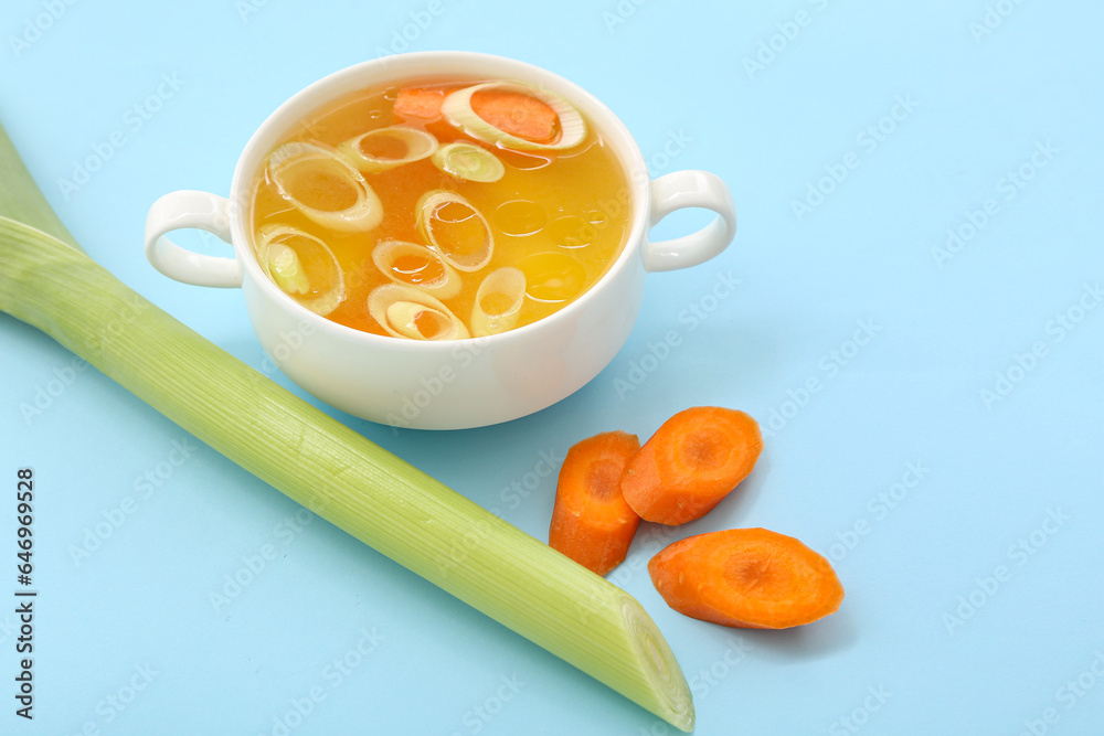 Pot of tasty vegetable broth on blue background