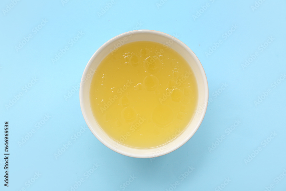 Bowl of tasty vegetable broth on blue background