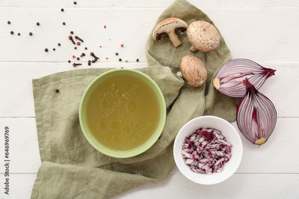 Bowl of tasty vegetable broth on white wooden background