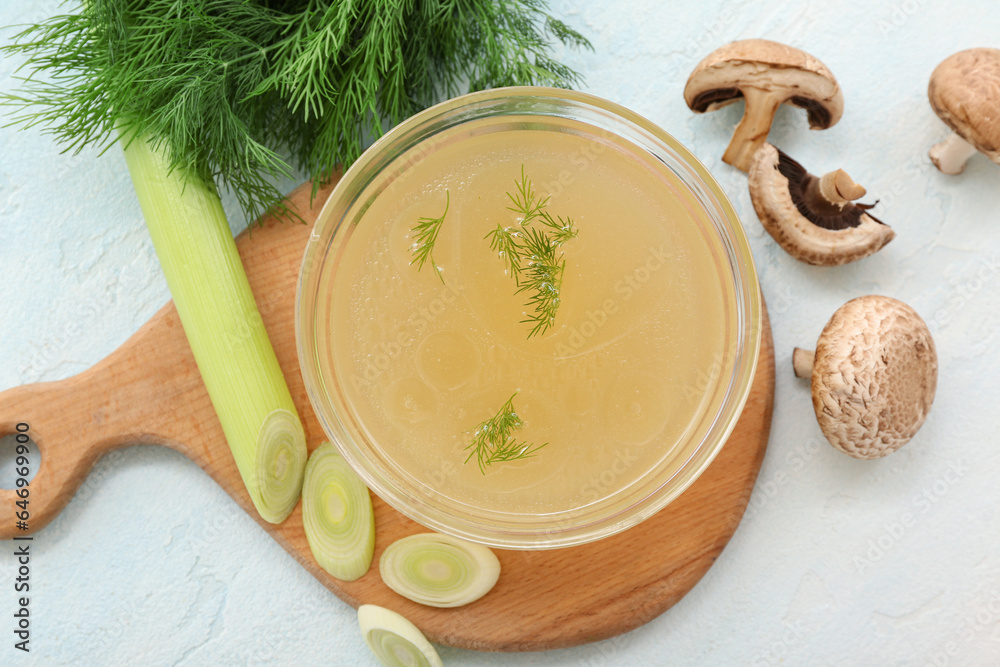 Bowl of tasty vegetable broth on light background