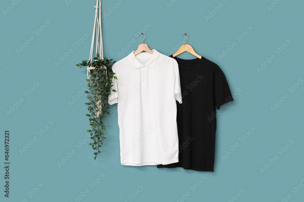 Stylish t-shirts hanging on blue background