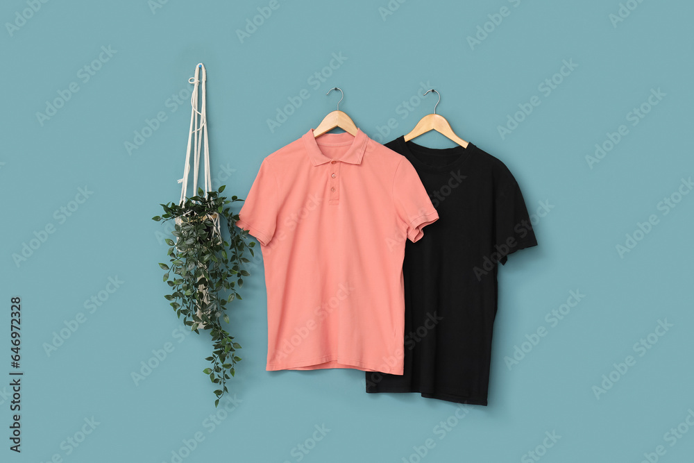 Stylish t-shirts hanging on blue background