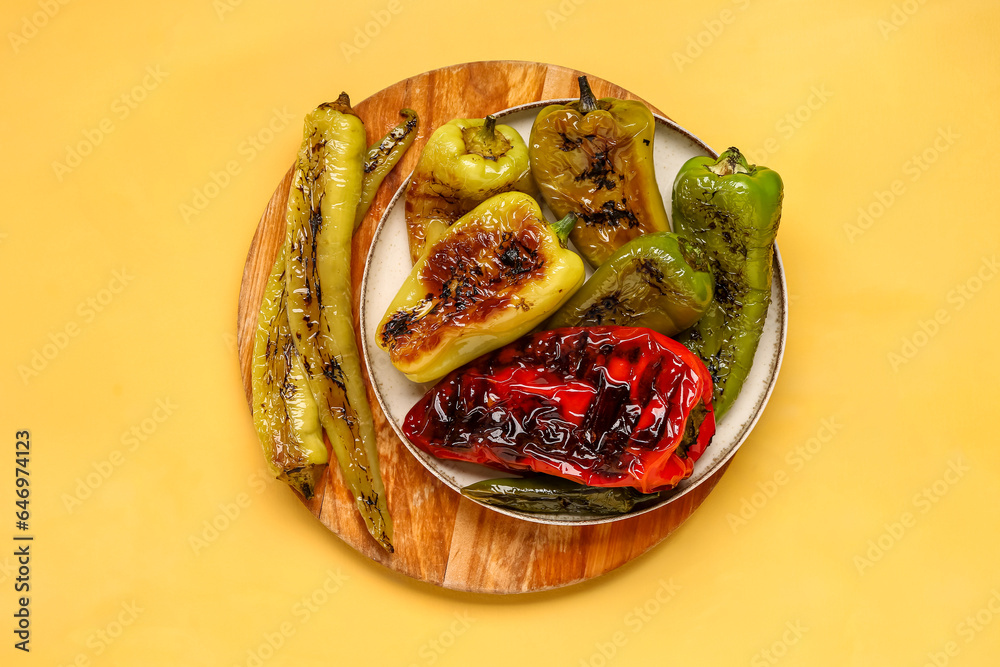 Plate with different grilled peppers on yellow background