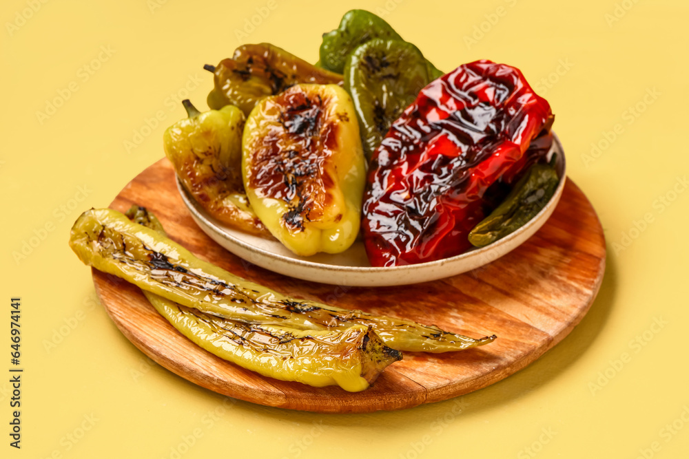 Plate with different grilled peppers on yellow background