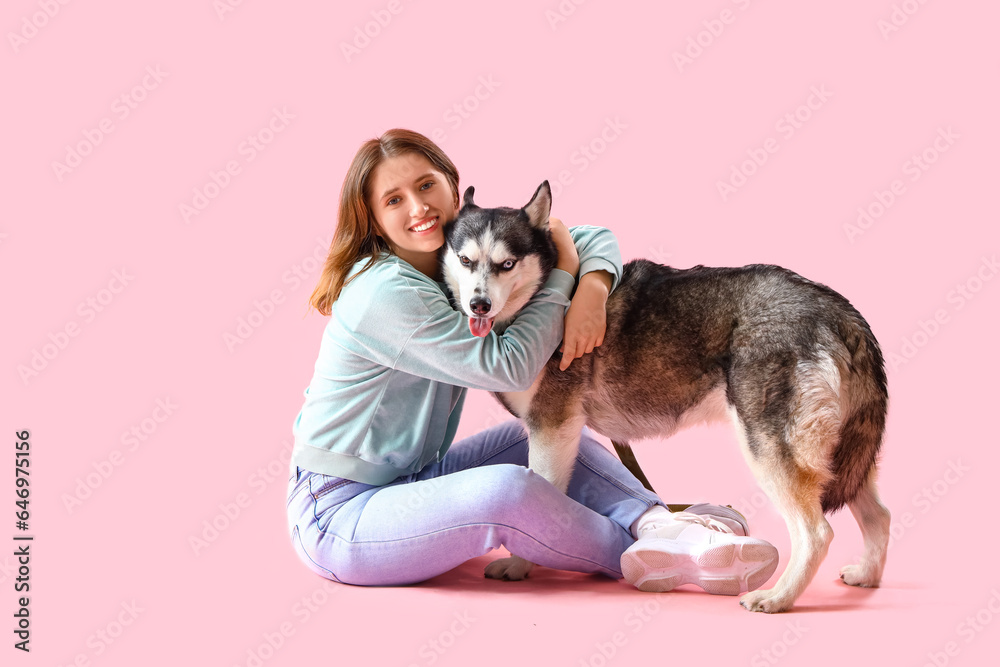 Happy young woman with husky dog on pink background