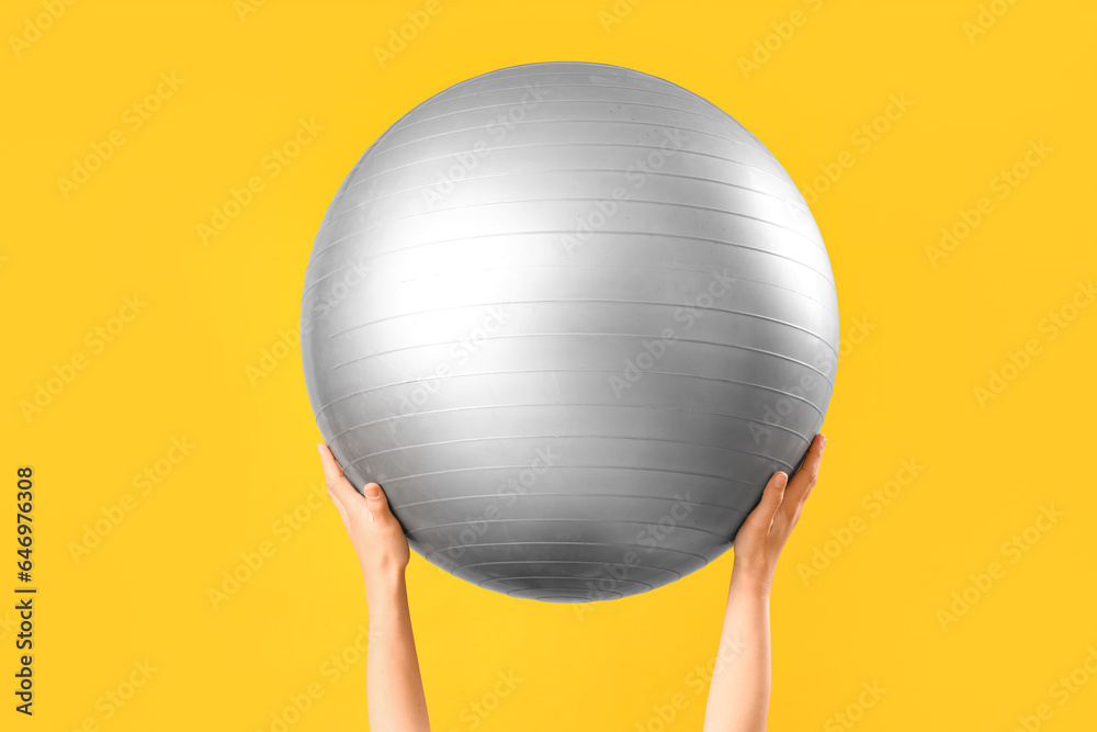 Woman holding fitness ball on orange background