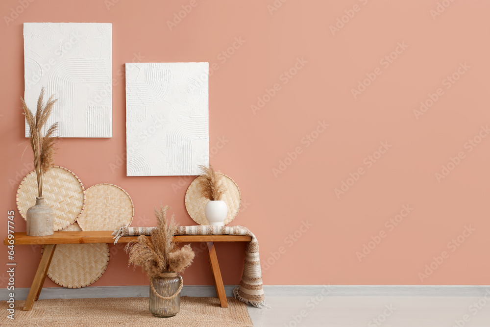 Wooden bench and dry floral decor in vases near pink wall in hall