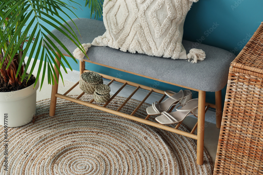 Bench with pillow, female accessories and houseplant near blue wall in hall