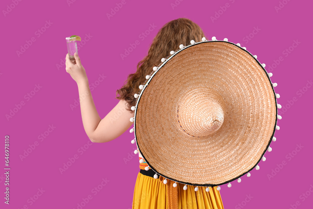 Happy Mexican woman with tequila on purple background, back view