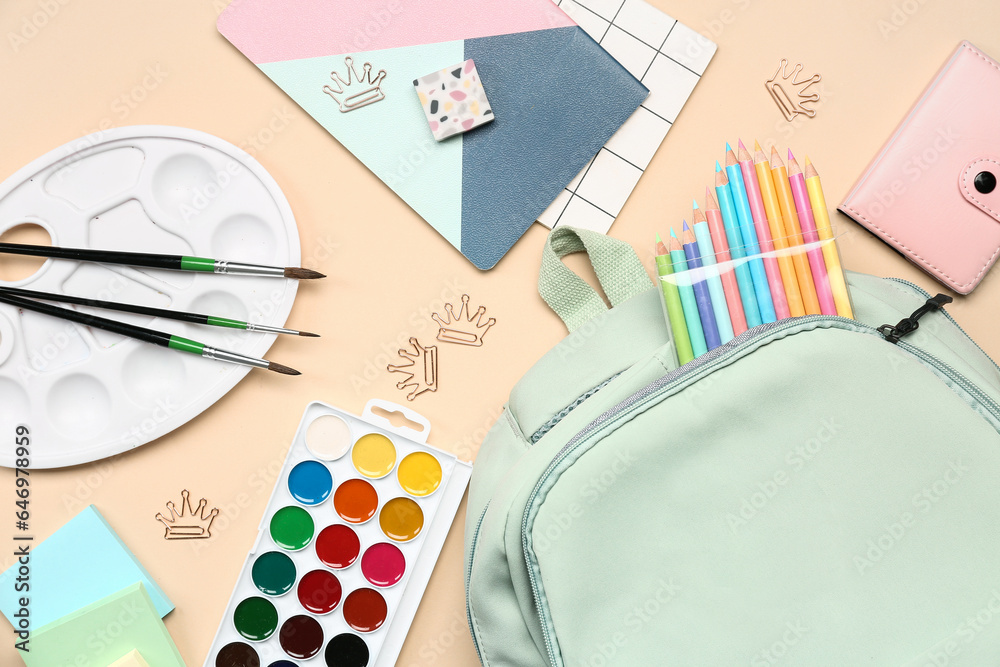 Stylish school backpack with different stationery supplies on beige background