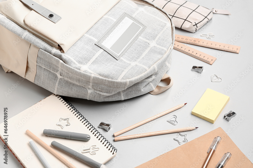 Stylish school backpack with different stationery supplies on grey background