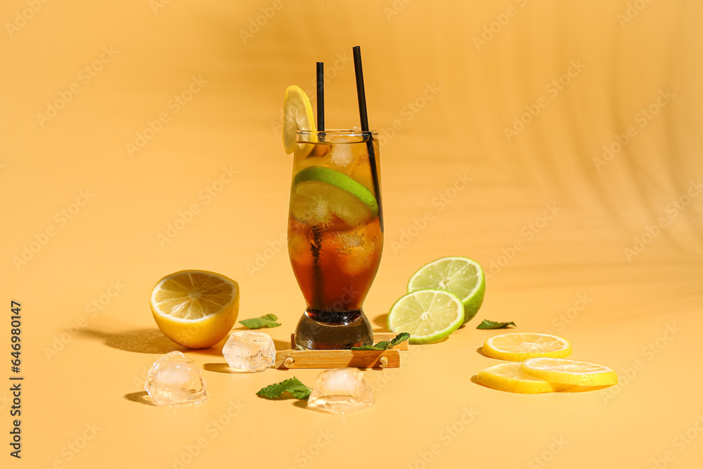 Glass of cold Long Island iced tea on light orange background