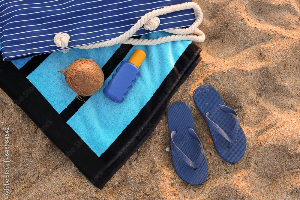 Stylish flips flops with beach accessories and coconut on sand at resort