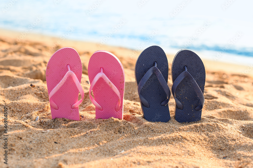 Stylish flips flops on sand near ocean at resort