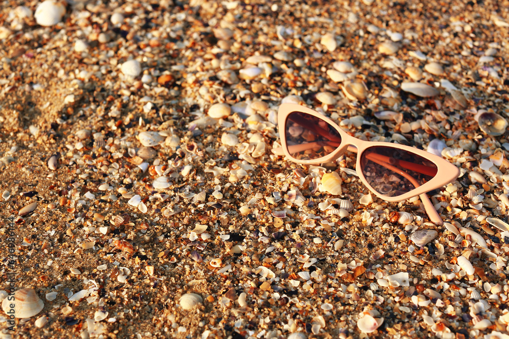 Stylish beige sunglasses on seashore