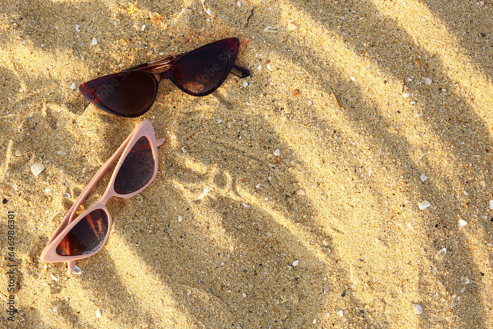 Different stylish sunglasses on sand