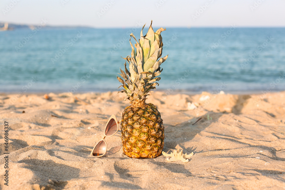 Stylish beige sunglasses with pineapple and starfish on seashore