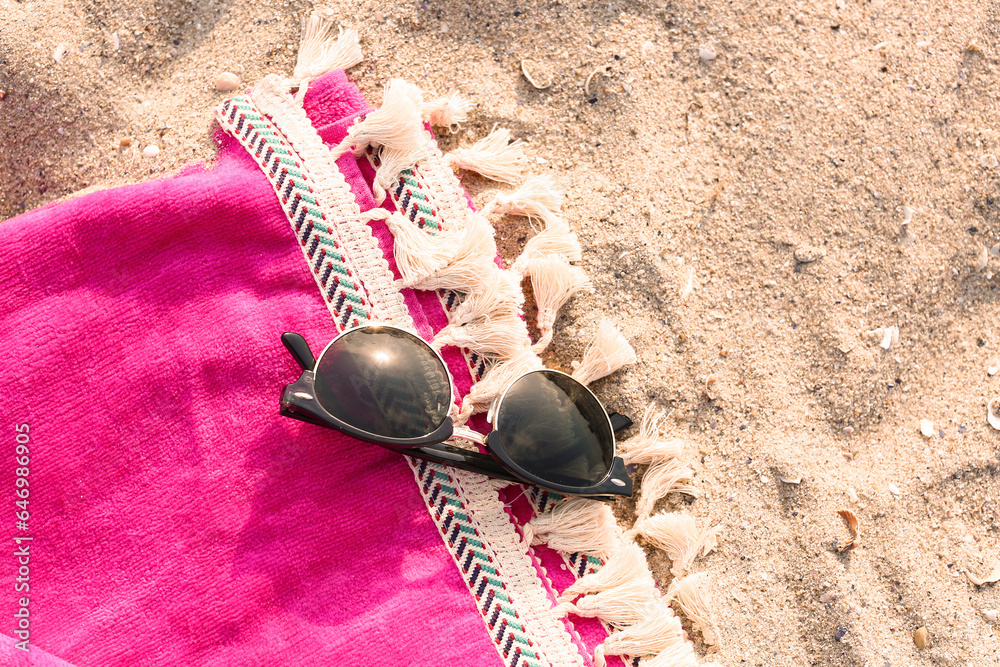 Stylish sunglasses on sandy background