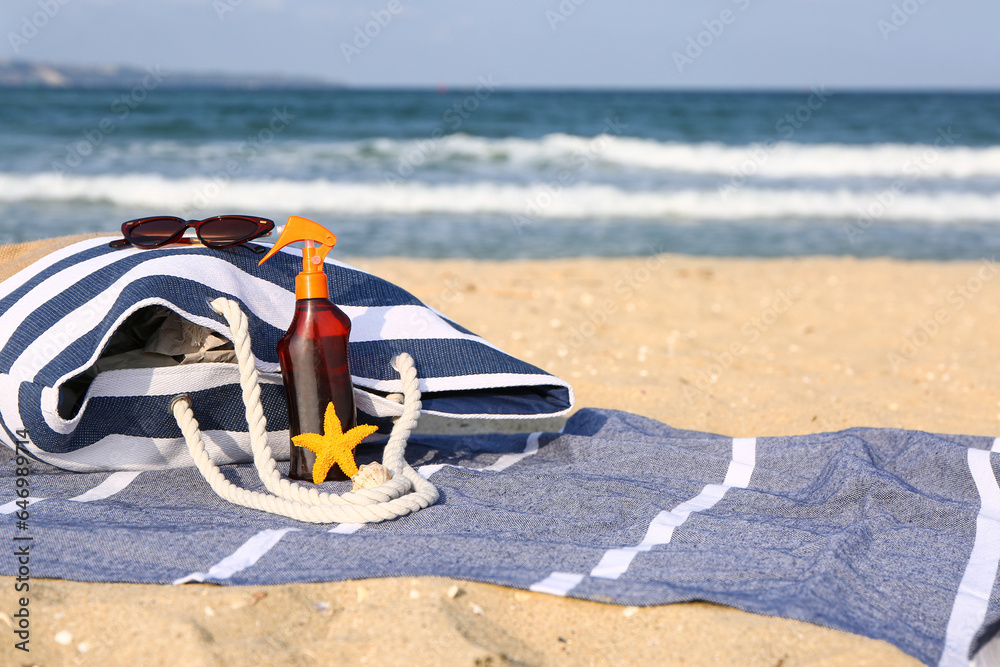 Towel with beach accessories on sand near sea