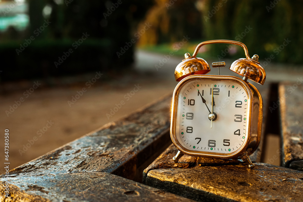 Vintage alarm clock on bench in park, closeup