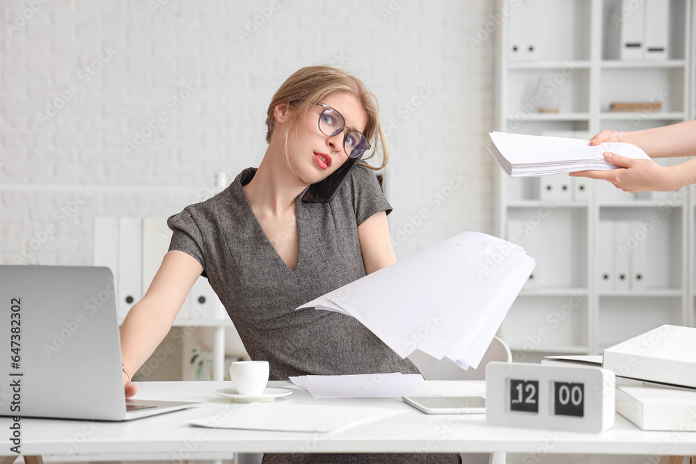 Young businesswoman working with documents under deadline in office