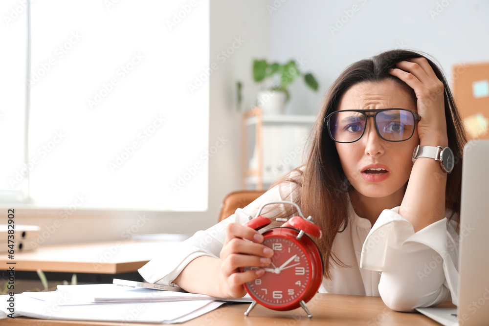 Stressed young businesswoman working under deadline in office