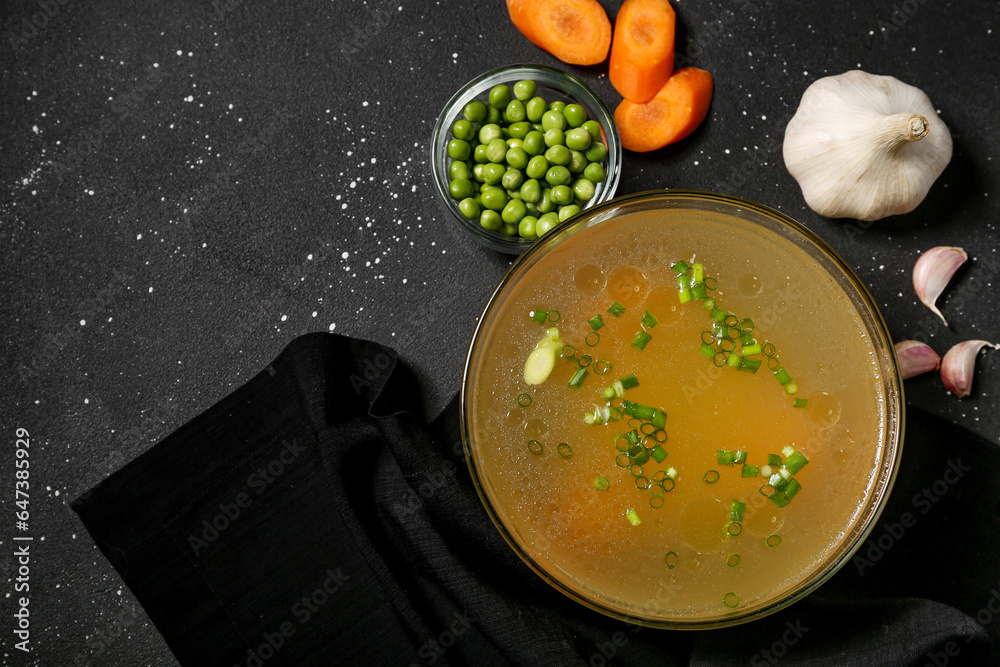 Bowl of tasty vegetable broth on black background