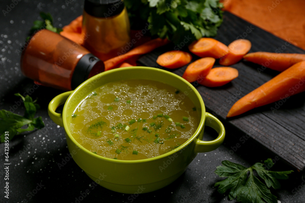 Pot of tasty vegetable broth on black background