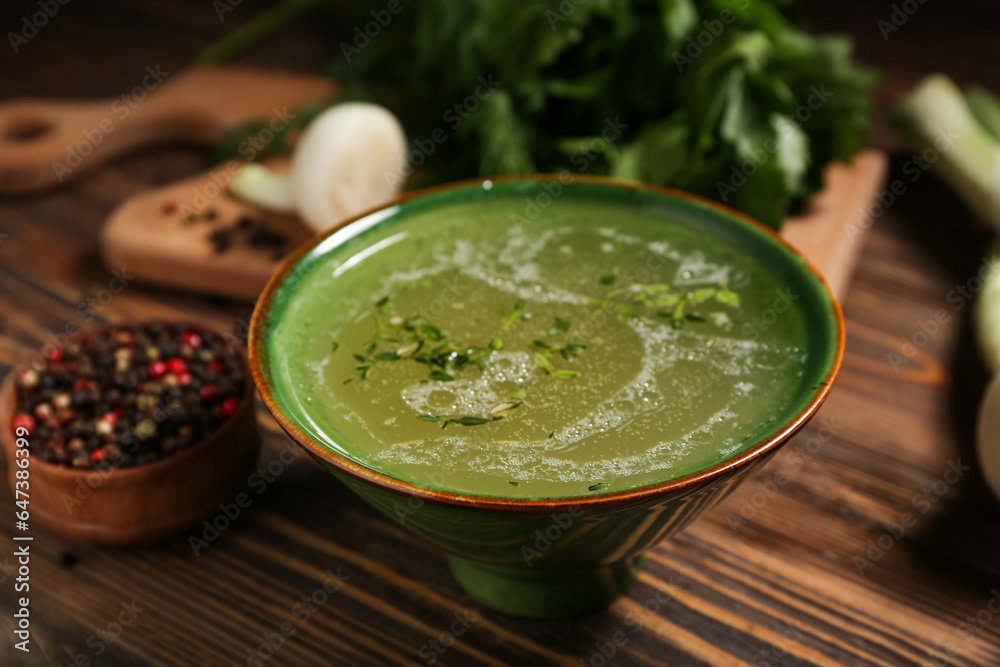 Bowl of tasty vegetable broth on wooden background