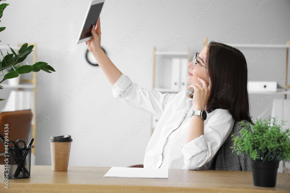 Young businesswoman with tablet computer video chatting in office