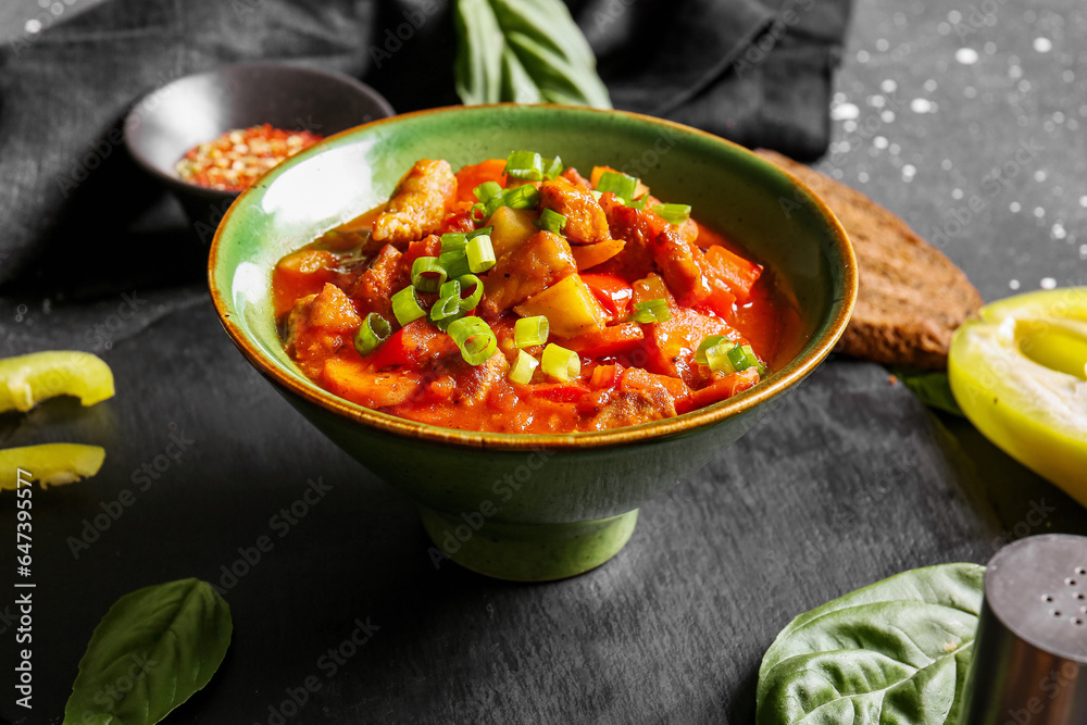 Bowl of tasty beef stew on black background