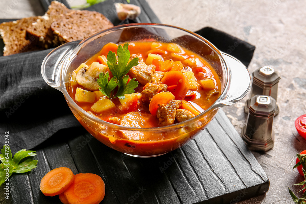 Pot of tasty beef stew on grey background