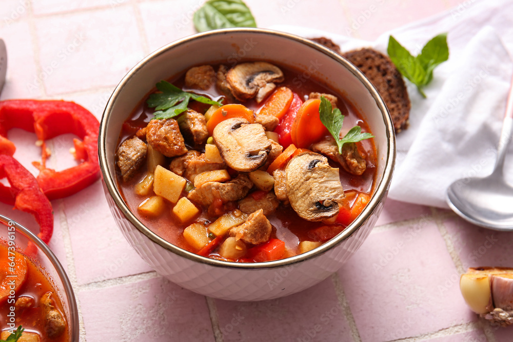 Bowl of tasty beef stew on pink tile background