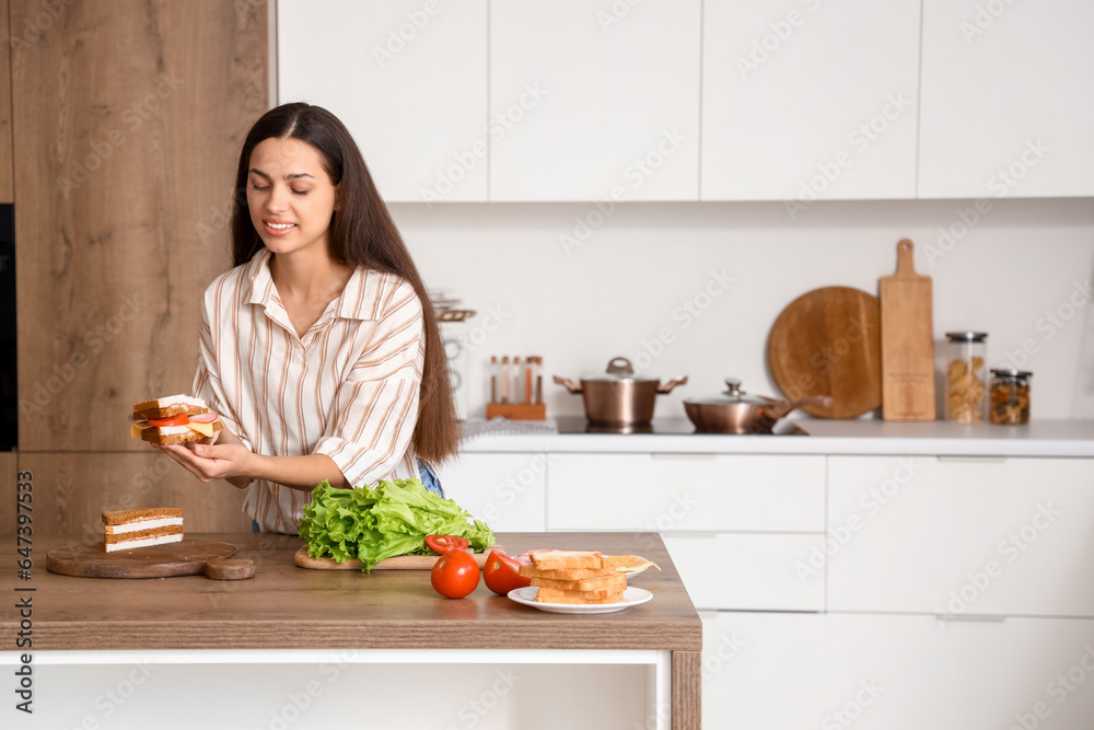 Young woman making tasty sandwich in kitchen