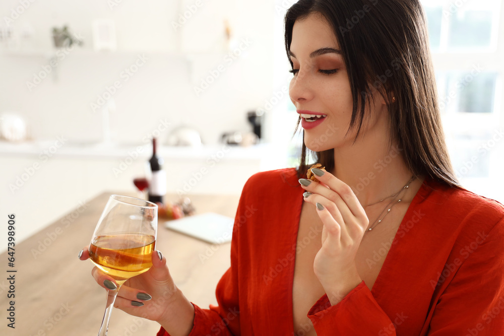 Young woman with glass of wine in kitchen, closeup