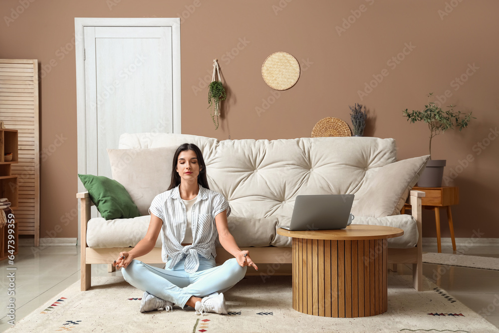 Young woman meditating on carpet in living room