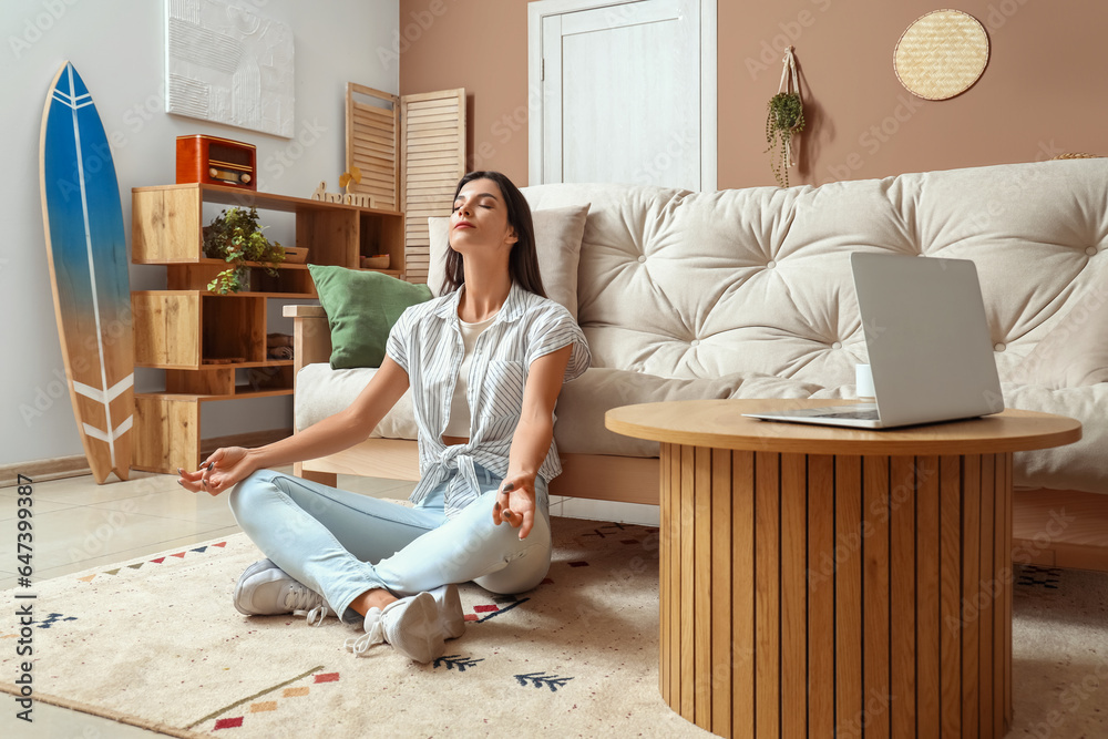 Young woman meditating on carpet in living room