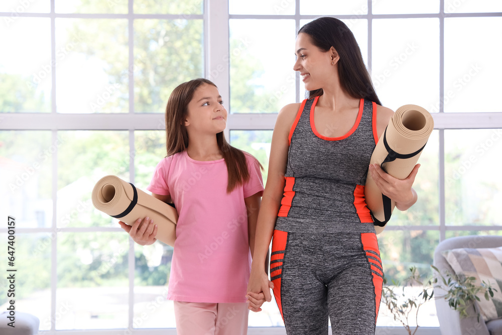 Sporty mother with her little daughter and fitness mats at home