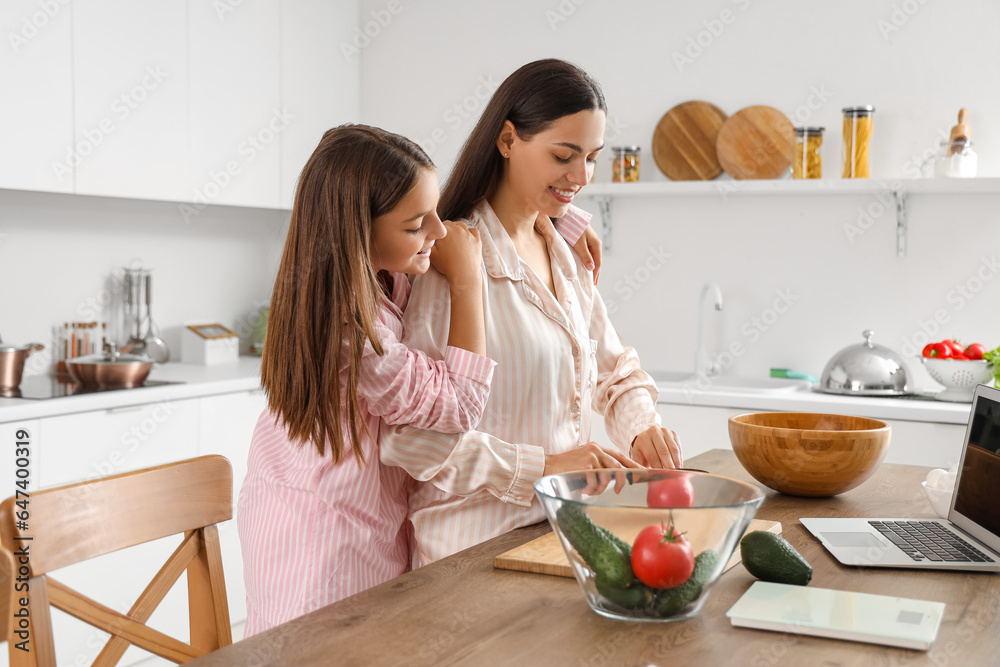 Happy mother with her little daughter cooking breakfast in kitchen