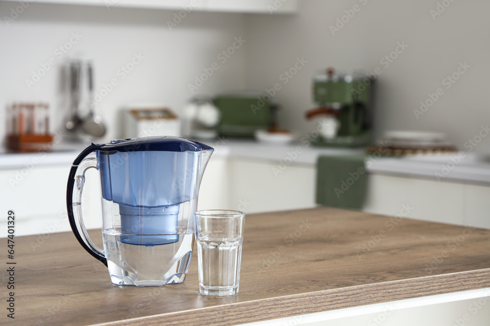 Blue water filter jug and glass on table in kitchen