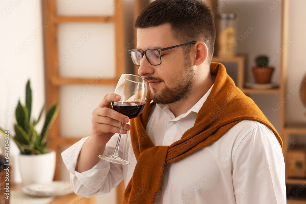 Young sommelier tasting wine in kitchen at home