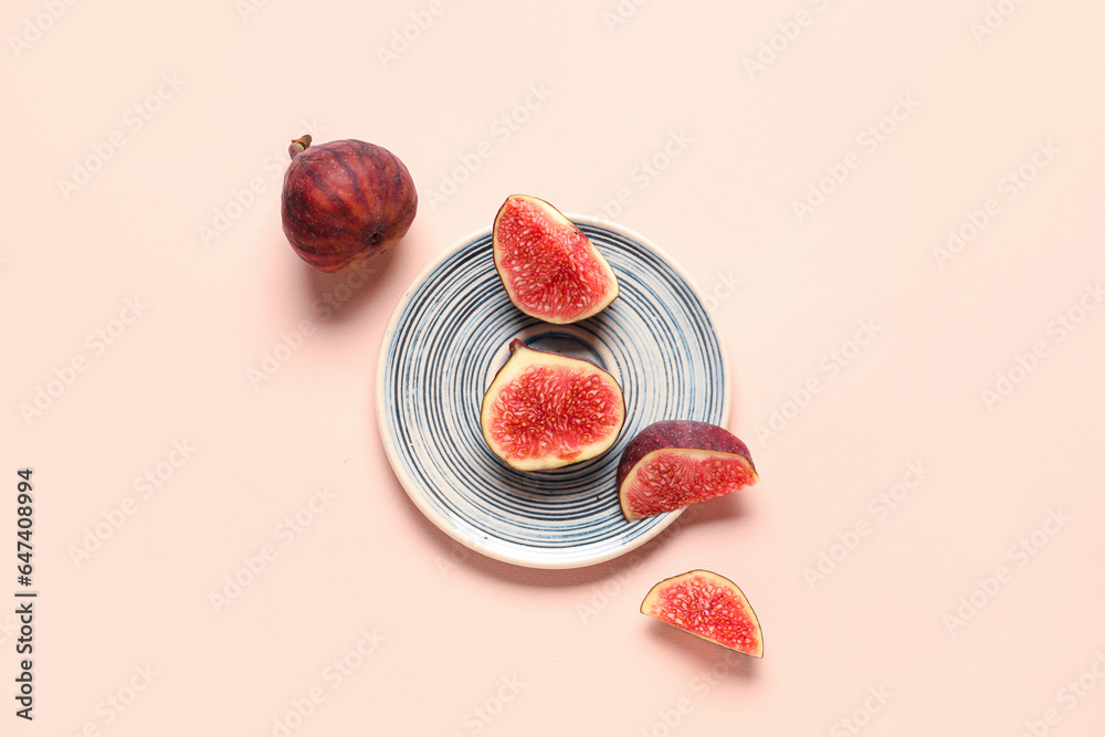 Plate with fresh juicy cut figs on pale pink background