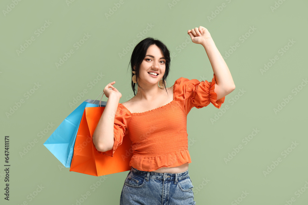 Beautiful happy woman with shopping bags on green background