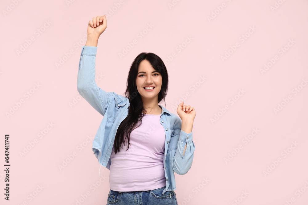 Portrait of happy dancing brunette on pink background