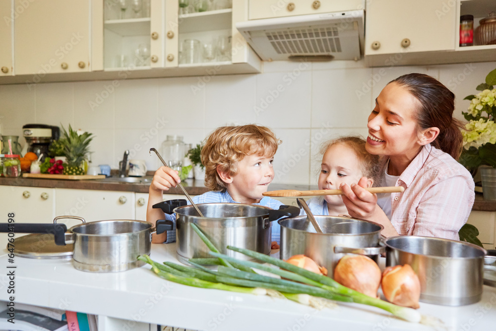 Family cooking together in kitchen with two children