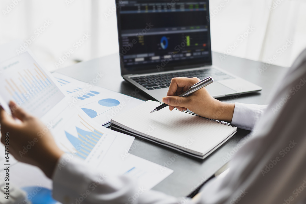 Businesswoman working on documents analyzing business finance charts and planning investments.