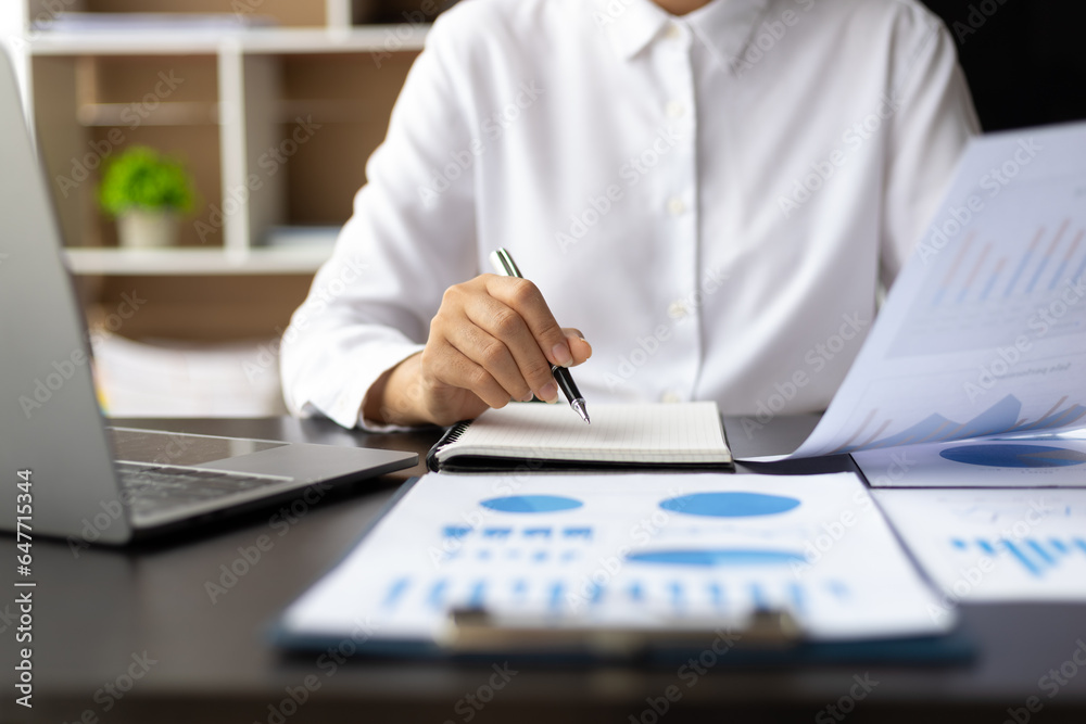 Businesswoman working on documents analyzing business finance charts and planning investments.