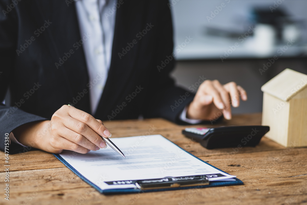 Businesswoman, real estate agent reading contract documents and calculating real estate budget.